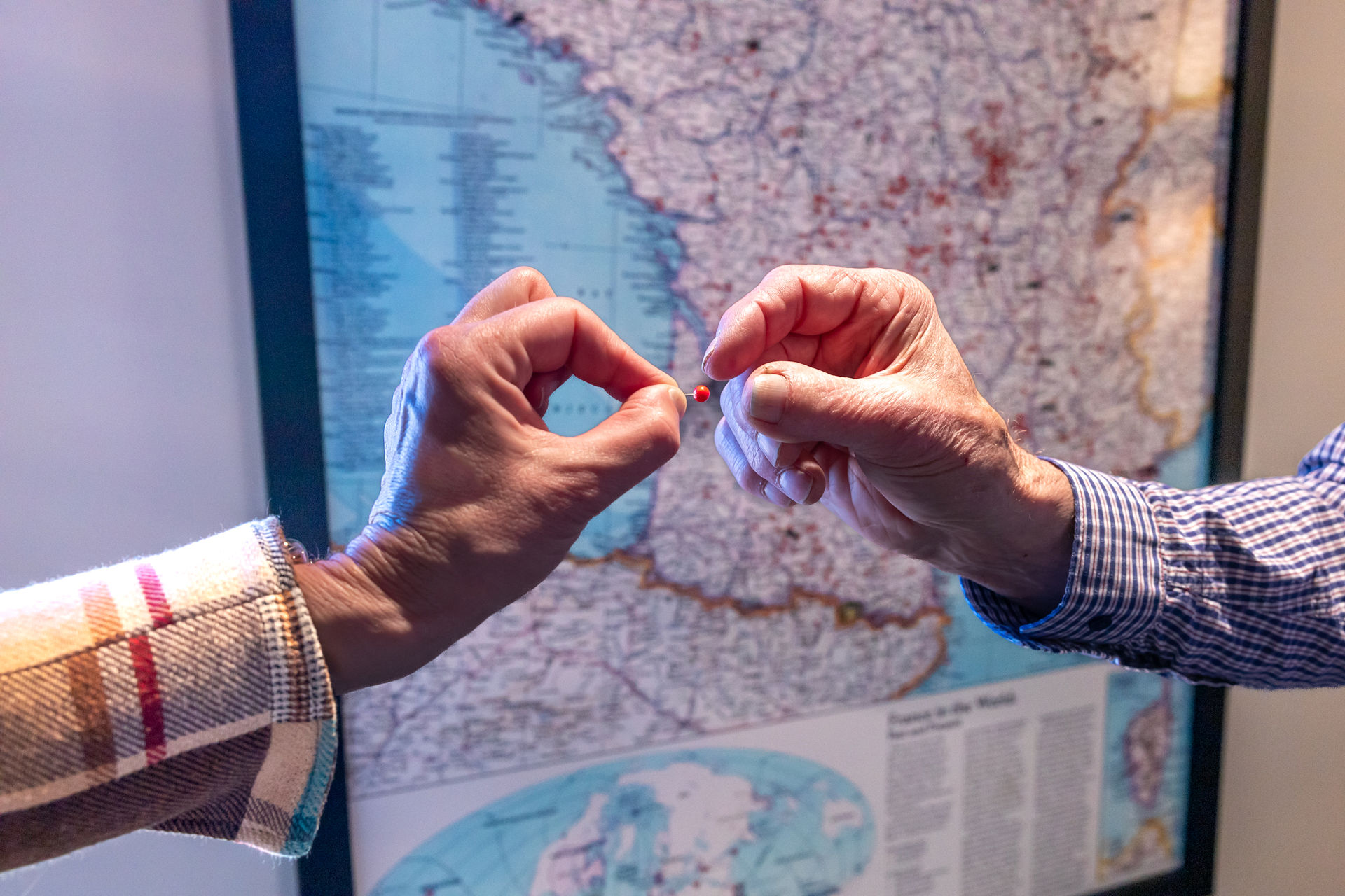 Twee handen plaatsen een speld op een landkaart